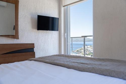 a bedroom with a bed with a television and a window at Oasis Sea view suit in Agia Marina Mikrolimanou