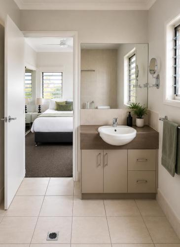 a bathroom with a sink and a bedroom with a bed at Emerald Inn by Travellers in Emerald