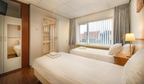 ein Hotelzimmer mit 2 Betten und einem Fenster in der Unterkunft Hotel-Pension Ouddorp in Ouddorp