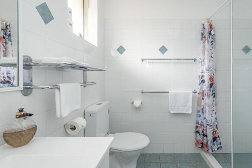 a white bathroom with a toilet and a sink at Emu Point Motel in Albany