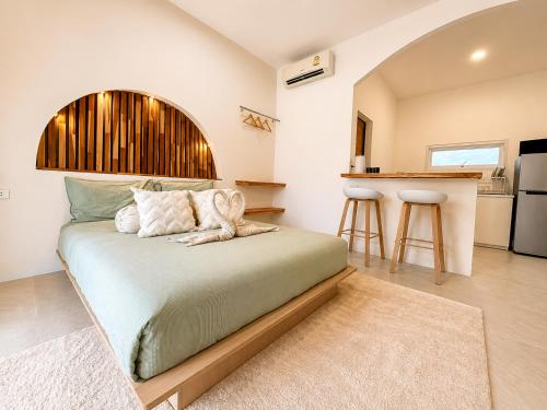 a bedroom with a large bed and a kitchen at Oh'lala Pool Cottages in Ban Tai