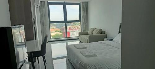 a bedroom with a bed and a chair and a window at CondoApsara in Phnom Penh
