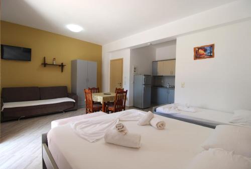 a bedroom with two beds and a kitchen and a table at Hotel Villa Kapo Pool & Bar in Ksamil