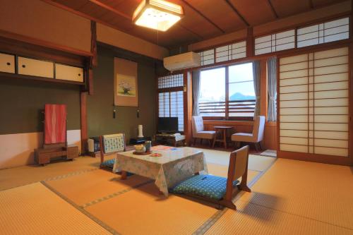 a living room with a table and chairs in a room at Ougiya Ryokan in Toyooka