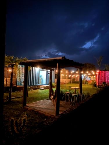 a gazebo with a table and chairs at night at POUSADAGiraGarden Containers in Arroio do Silva