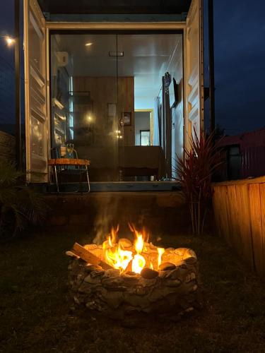 a fire pit in front of a house at night at POUSADAGiraGarden Containers in Arroio do Silva