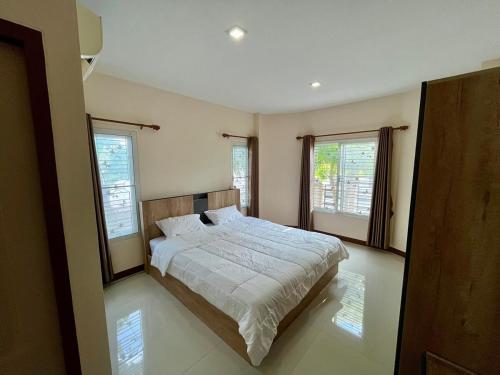 a bedroom with a large bed and two windows at BP Private Home in Ban Nong Sa