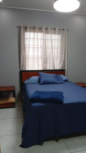 a bedroom with a blue bed with a window at Arbis Jusseth Home in Calobrito