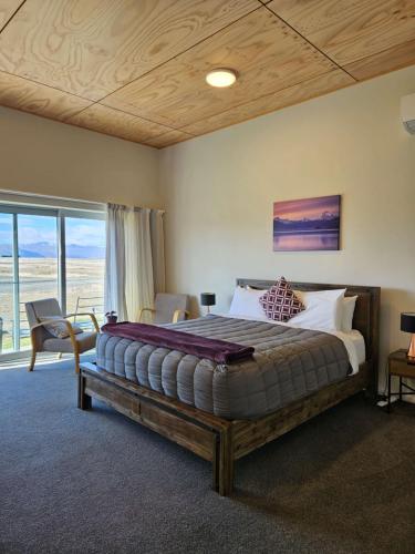 a bedroom with a large bed and a large window at Pukaki Air Lodge in Twizel