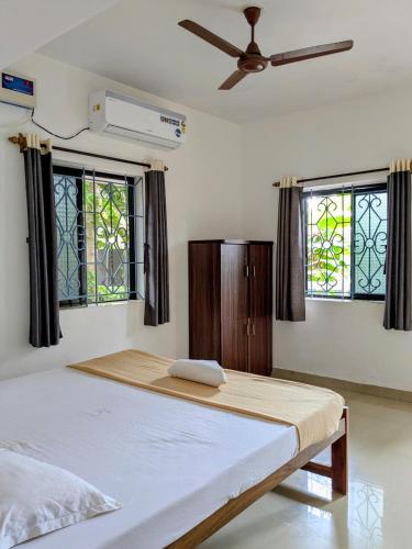 a bedroom with a bed and two windows at shivkrupa Guest house in Arambol