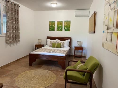 a bedroom with a bed and a green chair at La Marlyse in La Vatable