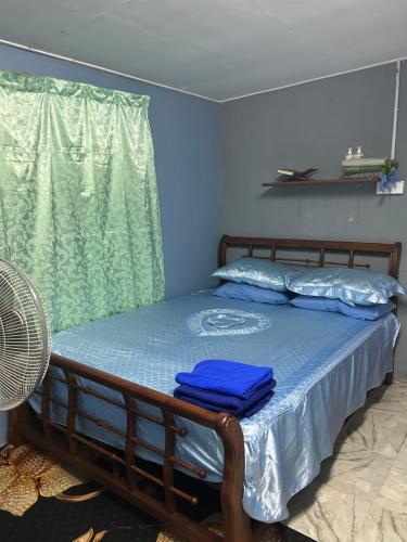 a bedroom with a bed with blue sheets and a window at Inap Desa Jalan Baru in Kampong Sedim Number Two