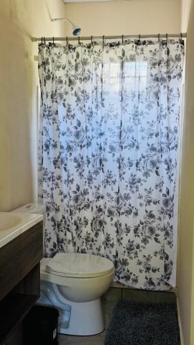 a bathroom with a toilet and a shower curtain at Hostal Casa Maros in Tamanique