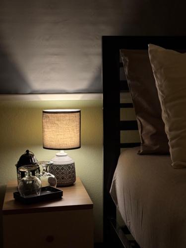 a bedroom with a bed and a lamp on a night stand at Chic Homestay Narathiwat in Ban Kam Pong Ba Ru