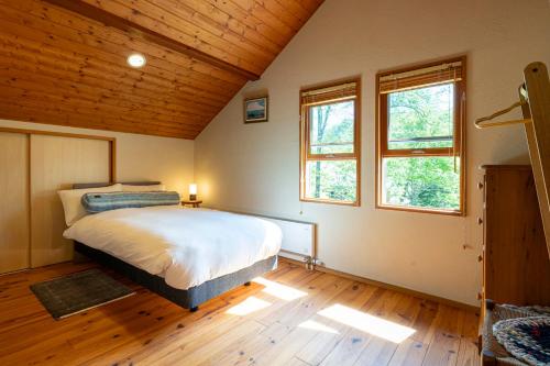 a bedroom with a bed and two windows at CALL92Chalet in Hakuba