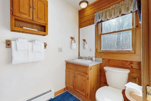 a bathroom with a toilet and a sink and a window at North Hill Cabin in Jay