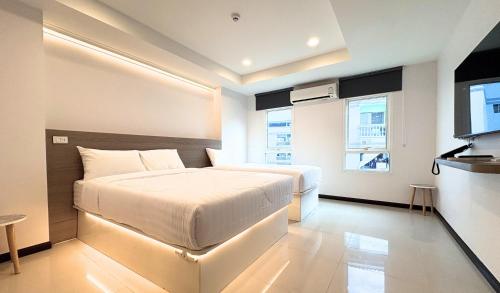 a bedroom with a white bed and a television at Paul and Pam Hotel Bangkok in Bang Kapi
