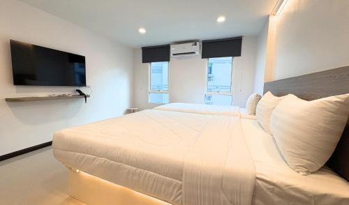 a bedroom with a large white bed with a flat screen tv at Paul and Pam Hotel Bangkok in Bang Kapi