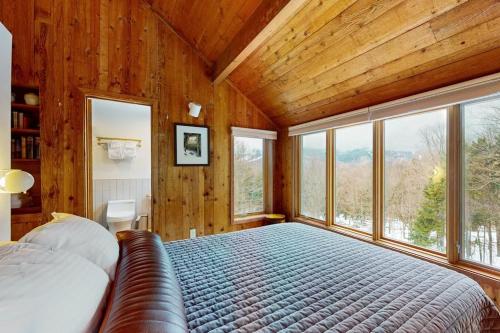 a bedroom with a large bed in a room with windows at Mad River Masterpiece in Irasville