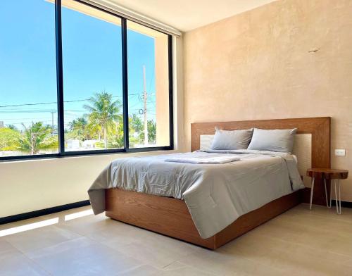 a bedroom with a bed and a large window at Villa oasis among the palms in Telchac Puerto