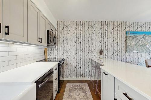 a kitchen with white cabinets and a wallpaper at Trail Creek 60 in Killington