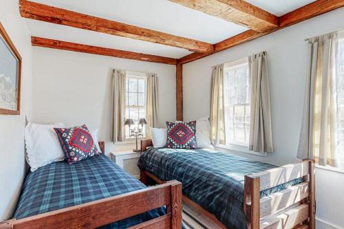 a bedroom with two beds and two windows at Vermont Mountain Farmhouse in Ludlow