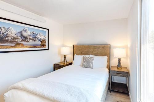 a white bedroom with a bed and two lamps at Fish Creek Point in Wilson