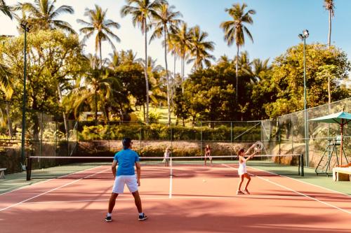 a group of people playing tennis on a tennis court at Villa Palem in Tabanan