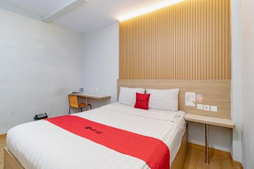 a bedroom with a large bed with a red blanket at RedDoorz Plus at Suba Hotel Tanjung Duren in Jakarta
