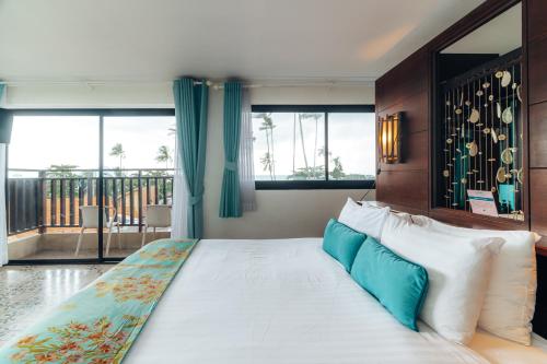 a bedroom with a large bed with blue and white pillows at Vacation Village Phra Nang Inn - SHA Extra Plus in Ao Nang Beach