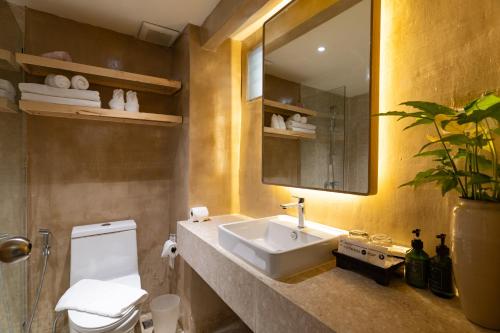 a bathroom with a sink and a toilet and a mirror at Vacation Village Phra Nang Inn - SHA Extra Plus in Ao Nang Beach