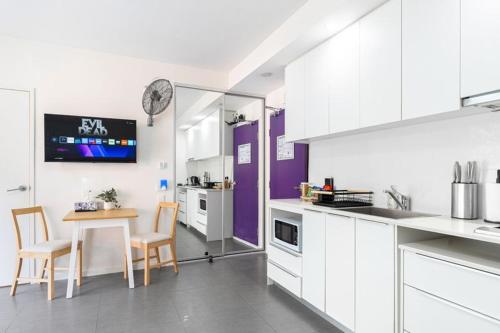 a kitchen with white cabinets and a table and chairs at 4B Relaxing Abnb Studio With Balcony, Near Marketplace And Train in Bankstown