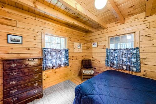 a log cabin bedroom with a bed and windows at Lake View Cottage in Leeds