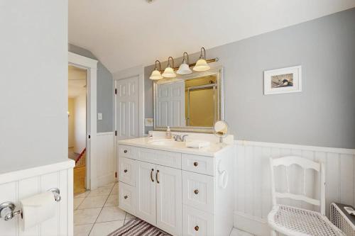 a white bathroom with a sink and a mirror at Quaint Bungalow in Kennebunk