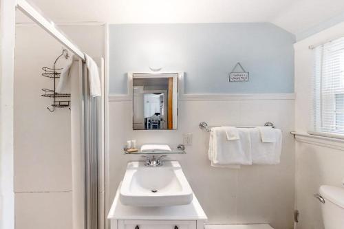 a white bathroom with a sink and a mirror at Old Orchard Cottage in Old Orchard Beach