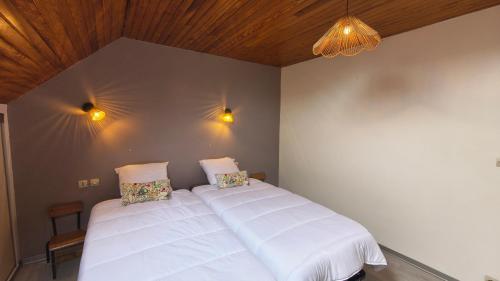 a bedroom with two white beds and a wooden ceiling at Gîte de la Verdière Spa Pool Valley in Le Sourn