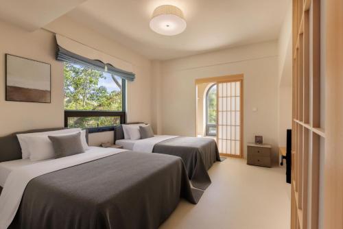 two beds in a room with two windows at Nanxiang Shushan Hotel in Sanya