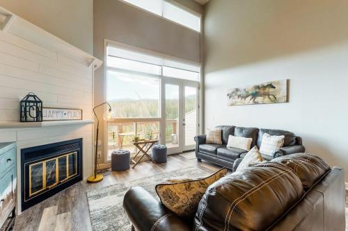 a living room with a leather couch and a fireplace at Watch Hill Lofted in Silverthorne