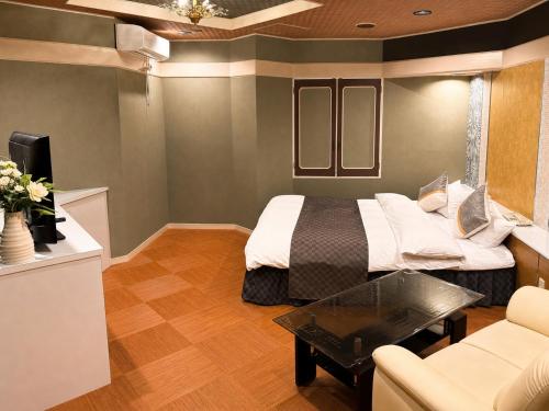 a bedroom with a bed and a couch and a table at Hotel WIN in Fukaya