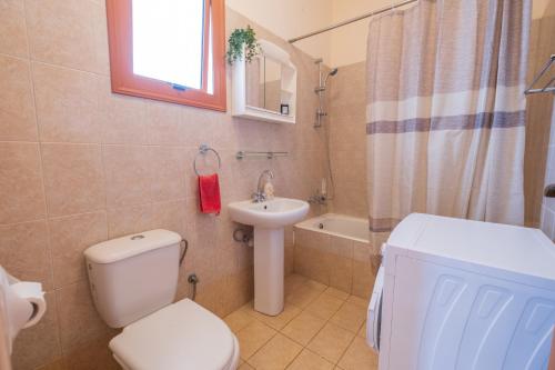 a bathroom with a toilet and a sink at Sunset Sea View Retreat with pool in Kissonerga
