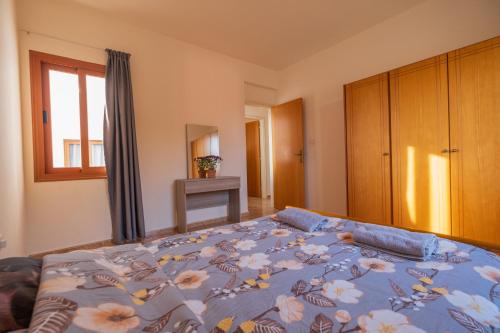 a bedroom with a bed with a blue comforter at Sunset Sea View Retreat with pool in Kissonerga