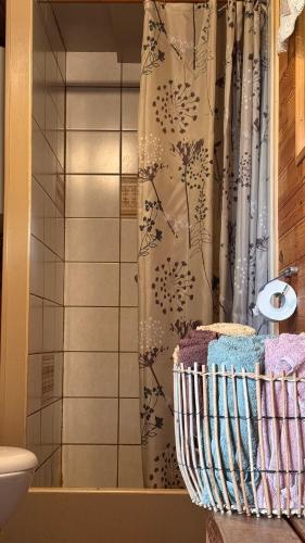 a bathroom with a shower curtain and a basket of towels at Viesu māja "Ozoliņi" in Jūrkalne
