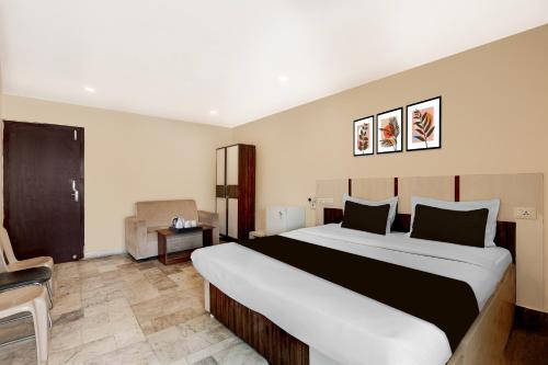 a hotel room with a large bed and a chair at Hotel O Benz Circle Crossway Vijayawada Formerly Akshaya Elite in Vijayawada