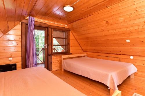 a bedroom with two beds in a log cabin at Ežero Panorama in Skirlėnai