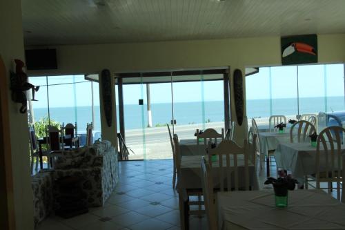 a restaurant with tables and chairs with a view of the ocean at Pousada Casa de Pedra in Boicucanga