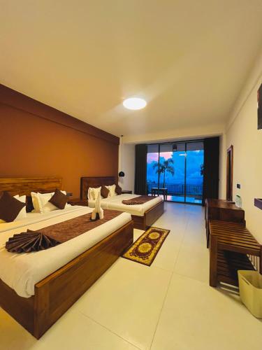 a hotel room with two beds and a large window at Srilak View Holiday Inn in Haputale