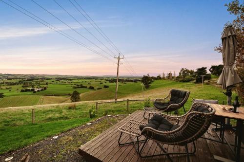 two chairs on a deck with a view of a field at Belrose Estate by Tiny Away in Dumbalk