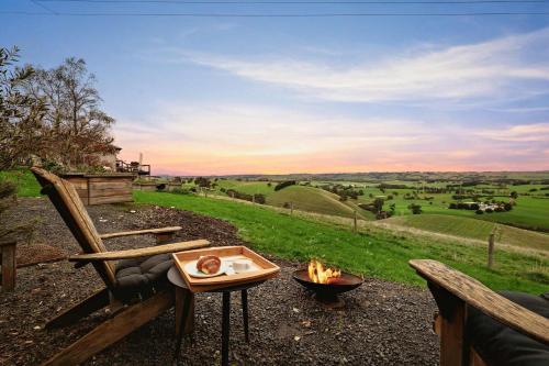 a fire pit with a table and a chair and a view at Belrose Estate by Tiny Away in Dumbalk