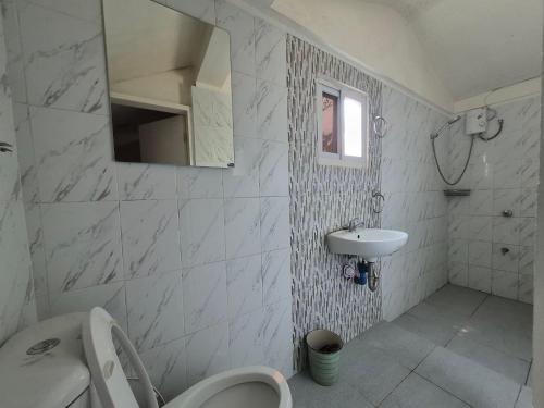 a white bathroom with a toilet and a sink at Beachfront AC Cave Cabin for 10pax in Caba