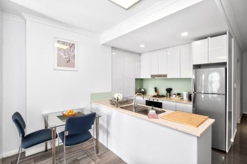 a kitchen with white cabinets and a table and chairs at 188 Apartments in Perth